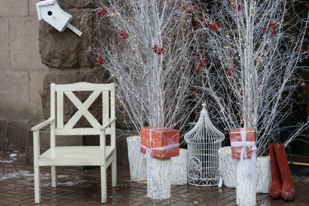 skromne biale krzeslo mikolaja w poblizu bialych drzew i pudelek z prezentami klatka na wakacje dla ptakow